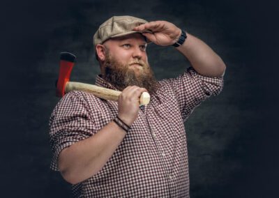 bearded man holds an axe and fire woods